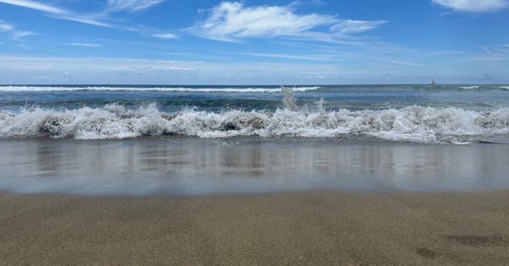 Idyllic sandy beach with gentle waves and vibrant blue sky. Perfect for relaxation and travel inspiration.